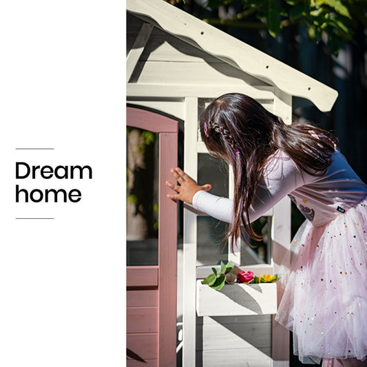 White and pink cottage cubby house, perfect for imaginative play in childrens outdoor spaces.