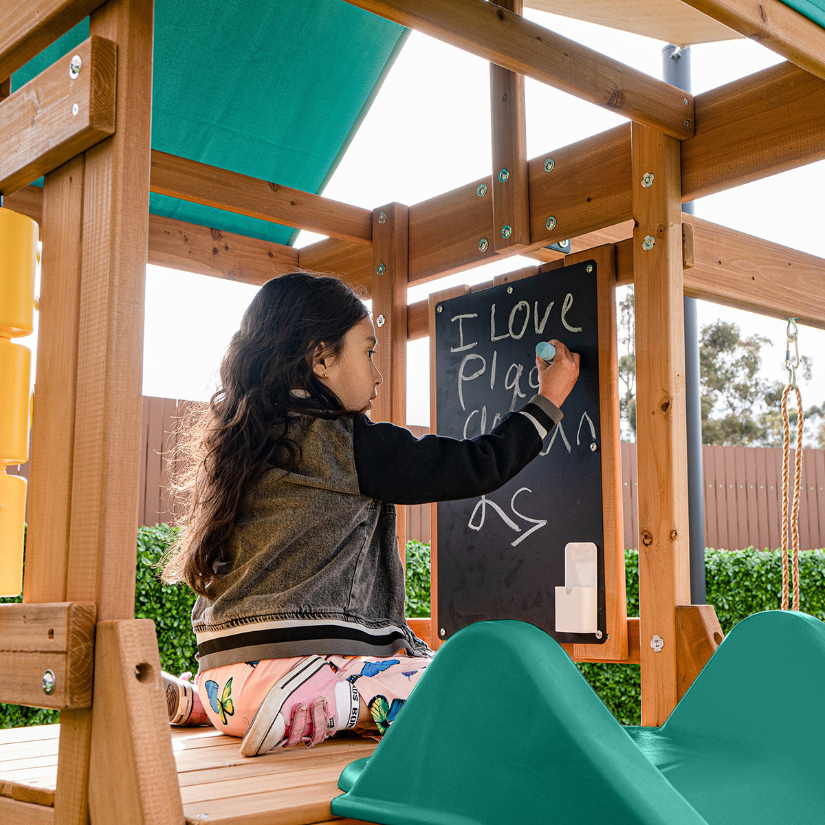 Raised playhouse with interactive chalkboard, telescope, and noughts & crosses game and green slide.