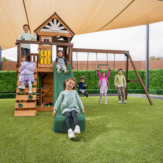 Outdoor play centre featuring a green slide, swings, and climbing wall for active backyard adventures.