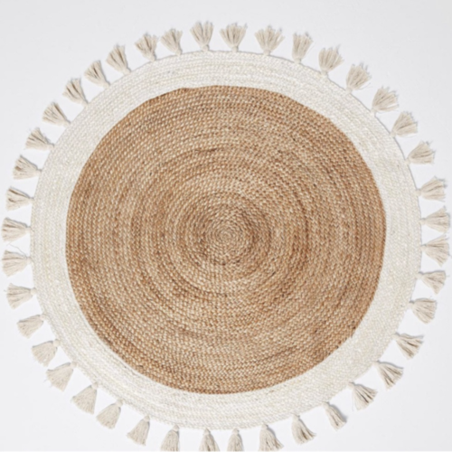 Bohemian round rug featuring jute, cotton, and tassel detail, perfect for childrens room decor.