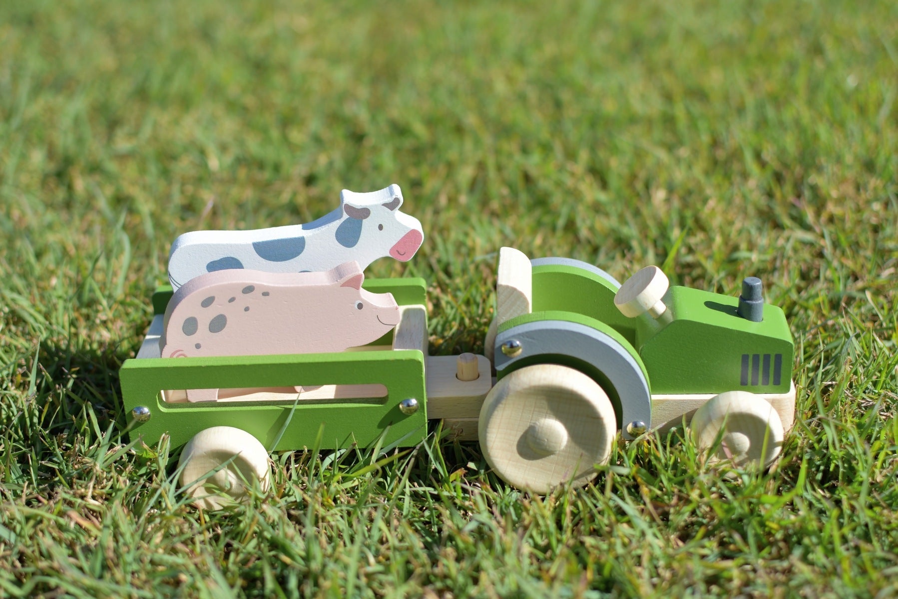 Wooden tractor toy with farm animal figures, perfect for imaginative play at home.